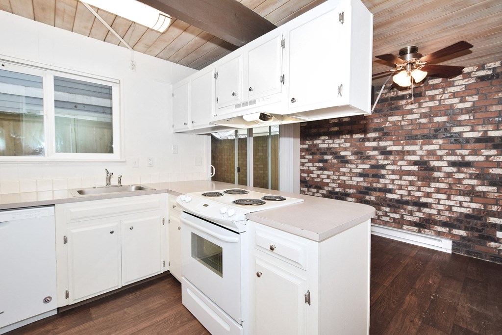 a kitchen with white cabinets and a brick wall