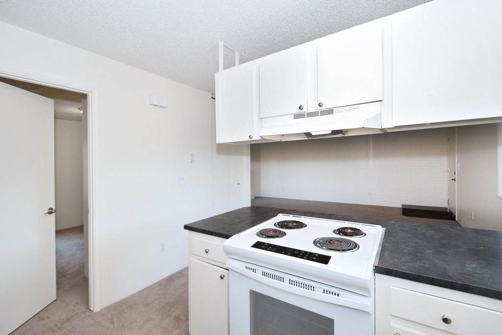 a kitchen with white cabinets and a white stove top oven