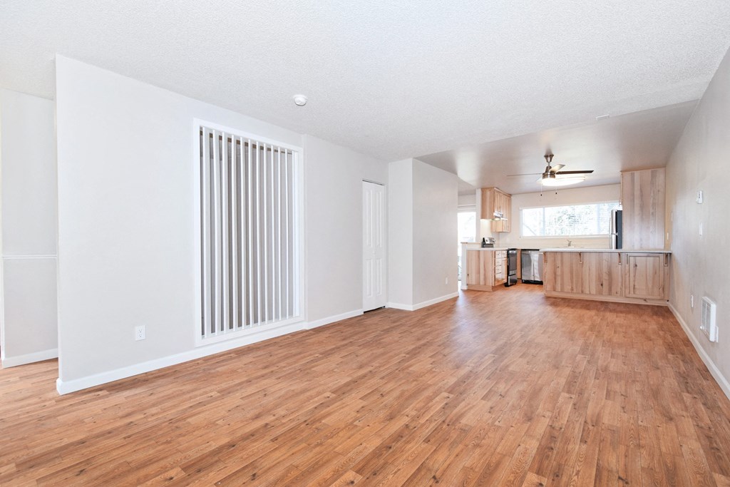 a living room with hardwood floors and a kitchen in the background