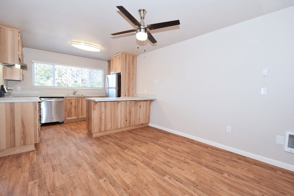 an open kitchen and living room with hardwood floors and a ceiling fan