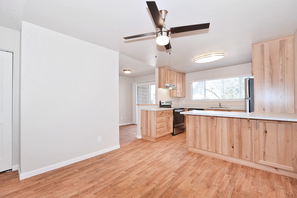 a kitchen and living room with hardwood floors and a ceiling fan