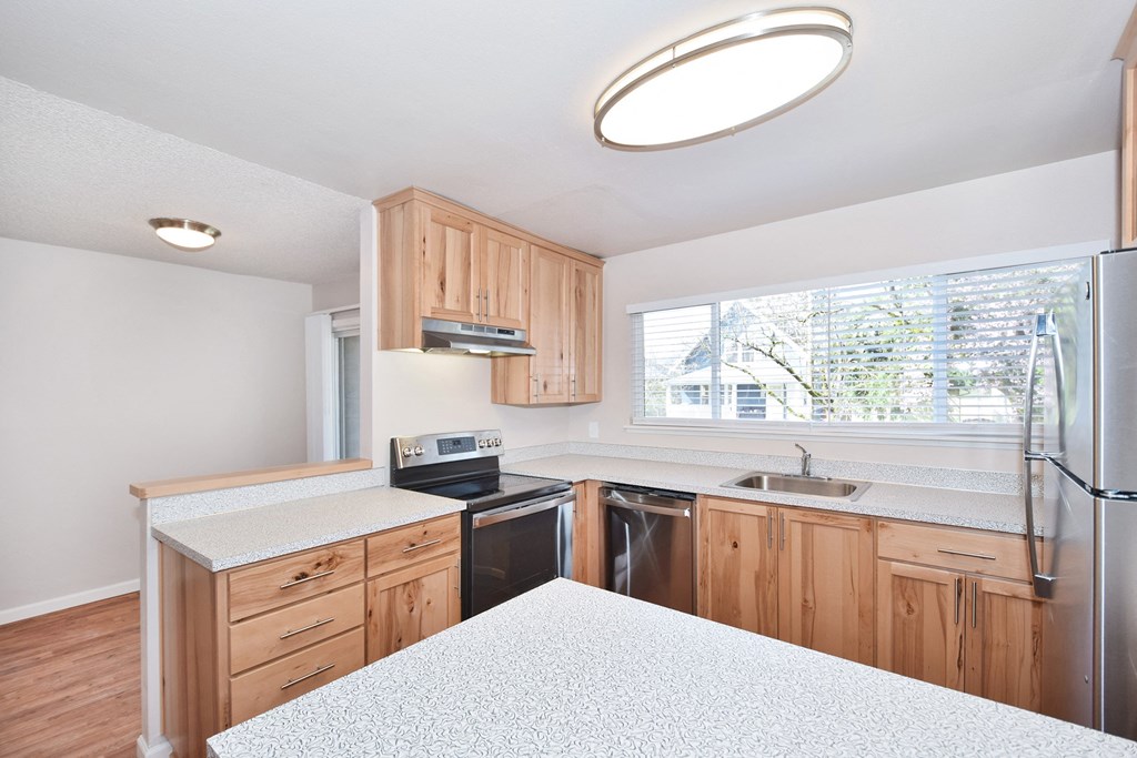 a kitchen with white countertops and wooden cabinets