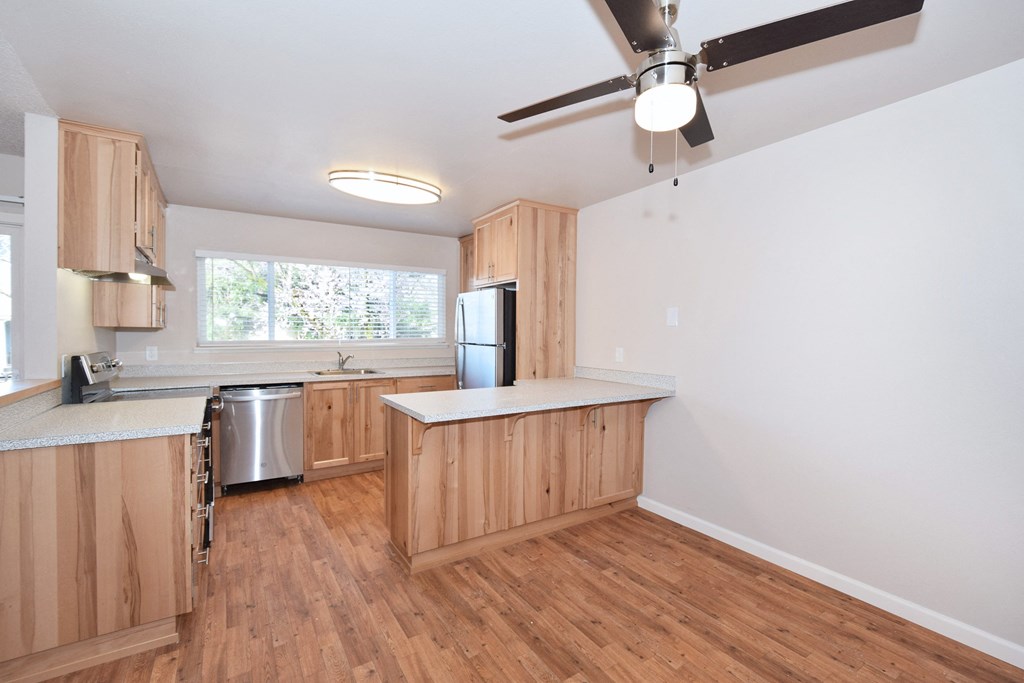 an empty kitchen with wood floors and a ceiling fan