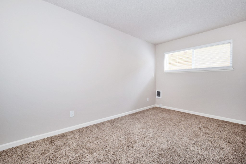 a bedroom with a carpeted floor and a small window