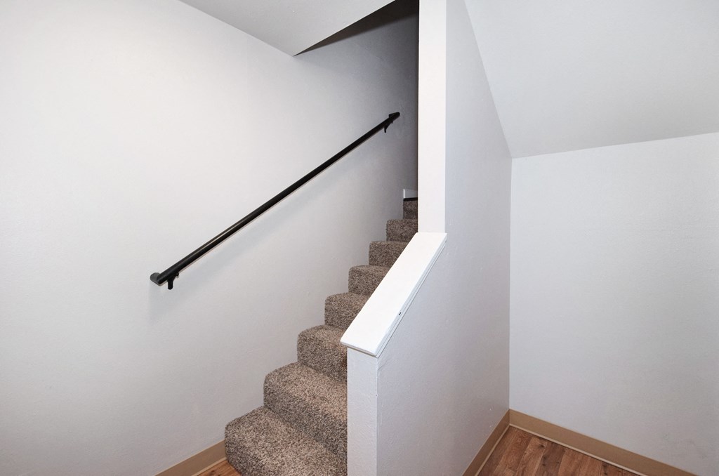 a stairwell in a home with white walls and carpet