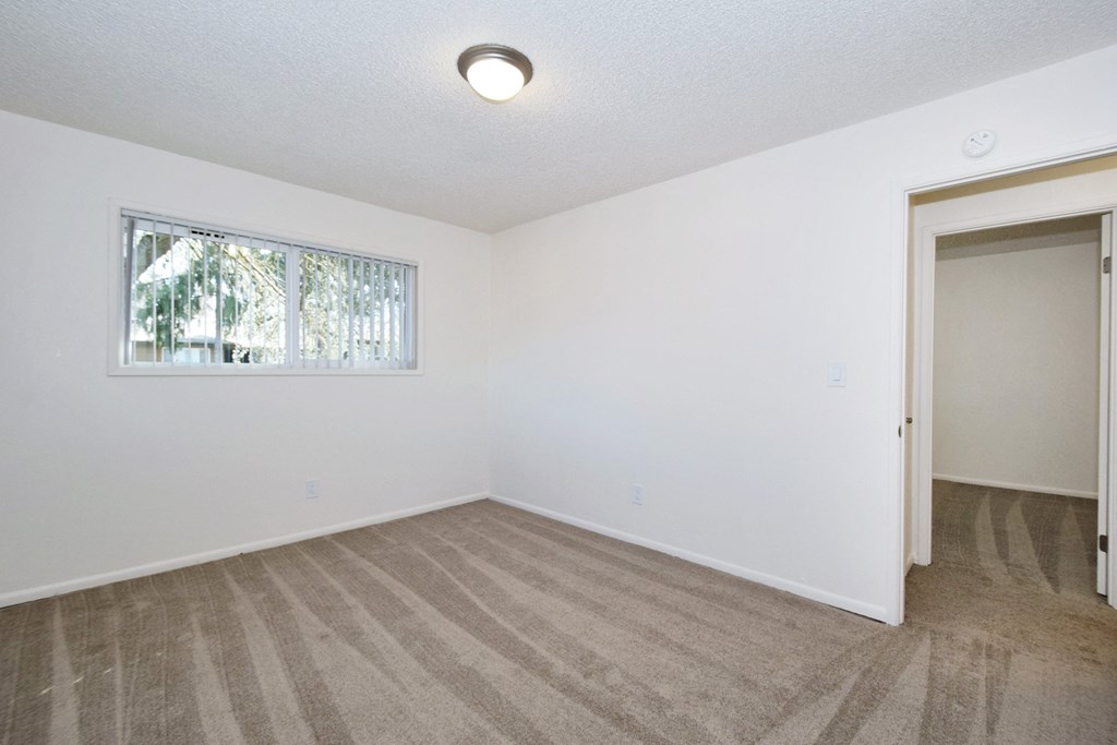 a bedroom with white walls and a window