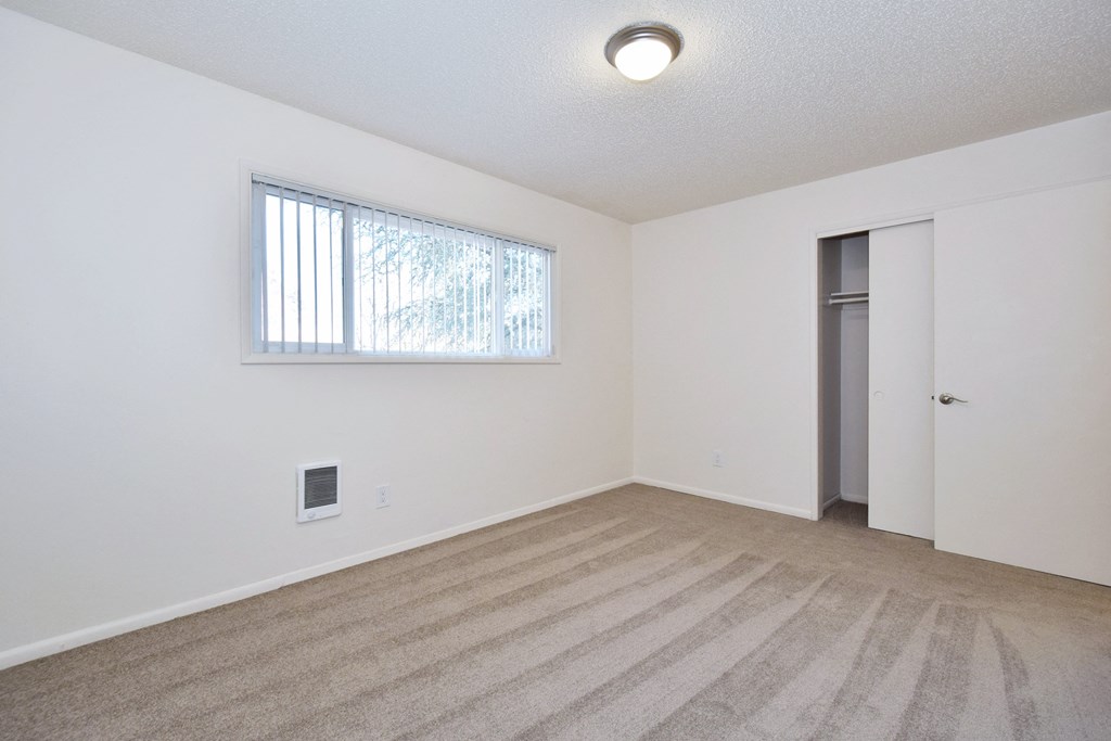 a bedroom with a large window and a carpeted floor