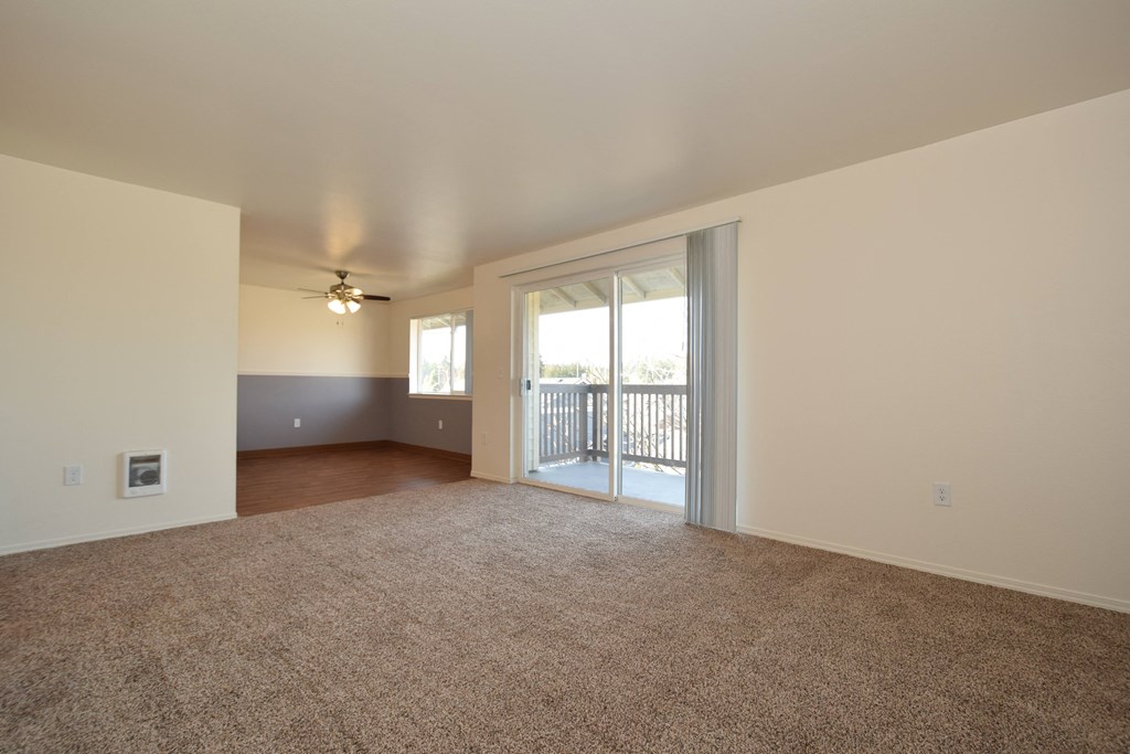an empty living room with a sliding glass door and a balcony