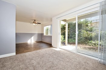 an empty living room with a sliding glass door and a ceiling fan - Photo Gallery 68