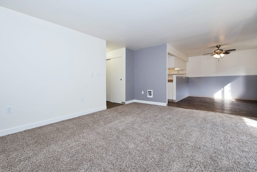 an empty living room with a ceiling fan
