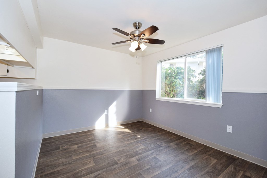 an empty room with a ceiling fan and a window