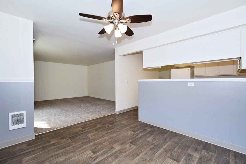 an empty living room with a ceiling fan