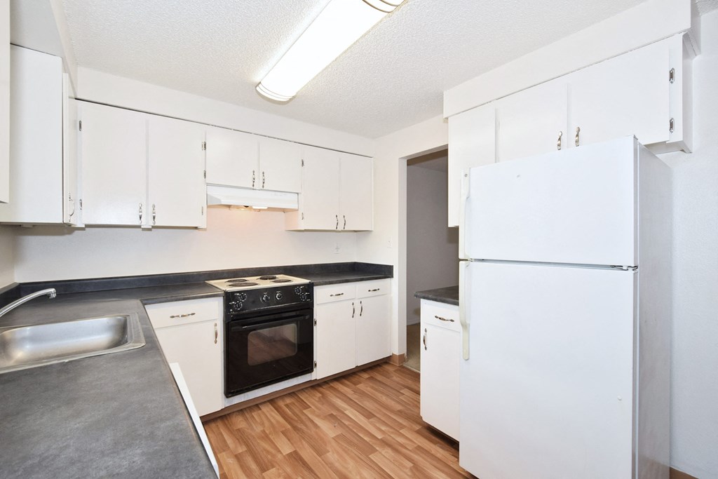 The Firs:  a kitchen with white cabinets and black countertops