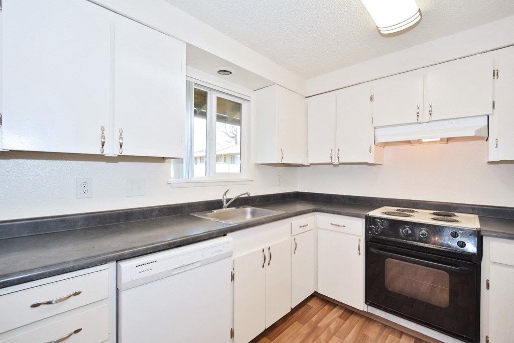 The Firs:  a kitchen with white cabinets and a black counter top