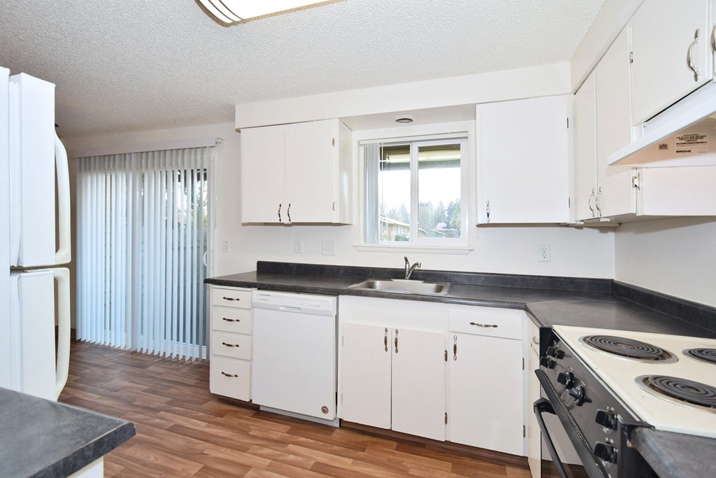 The Firs:  a kitchen with white cabinets and a wood floor