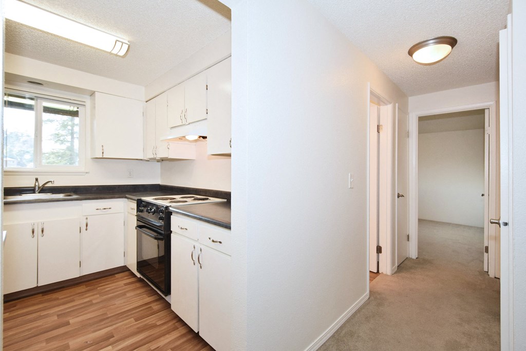 The Firs: a kitchen with white cabinets and black countertops