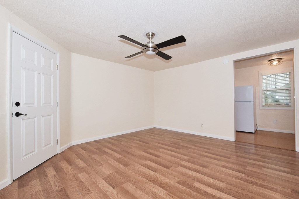 an empty living room with a ceiling fan and a closet