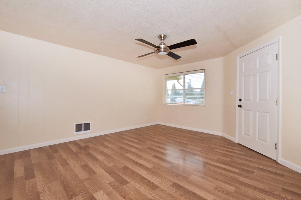 the living room of an empty home with a ceiling fan