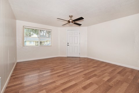 an empty living room with a ceiling fan and a window