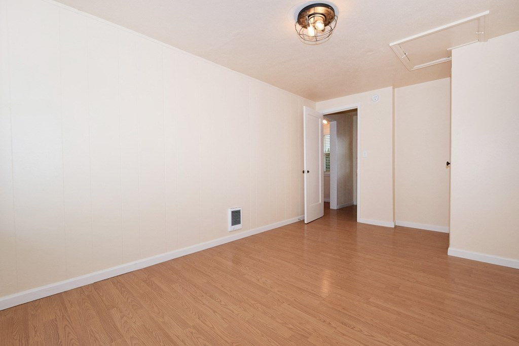 an empty living room with wood floors and white walls