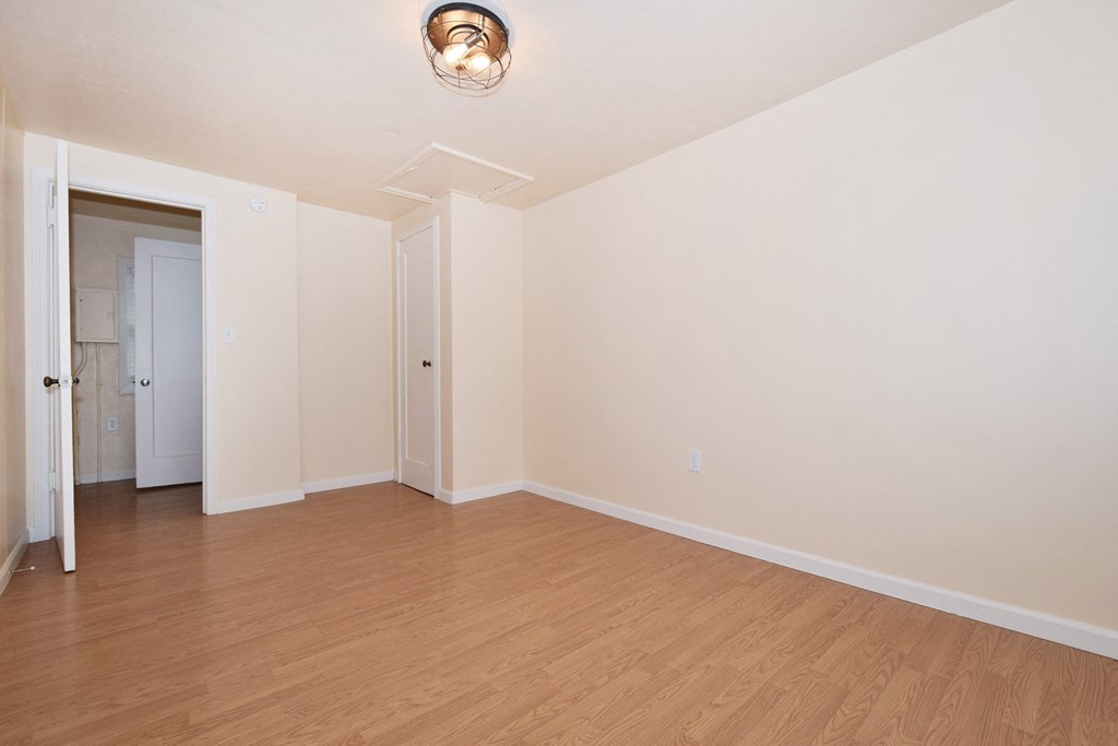 an empty living room with wood floors and white walls