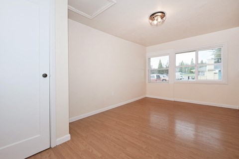 an empty living room with wood floors and white walls