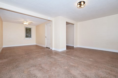 an empty living room with carpet and a ceiling fan