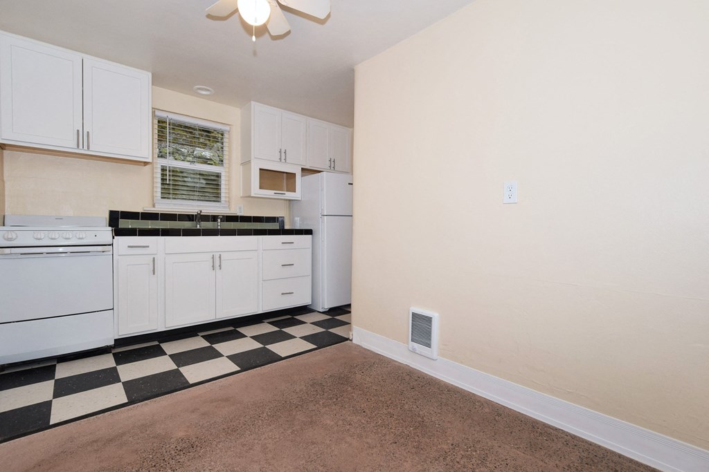 an empty kitchen with white appliances and black and white checkered floor