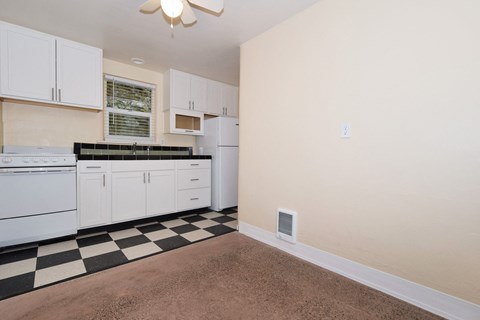an empty kitchen with white appliances and black and white checkered floor