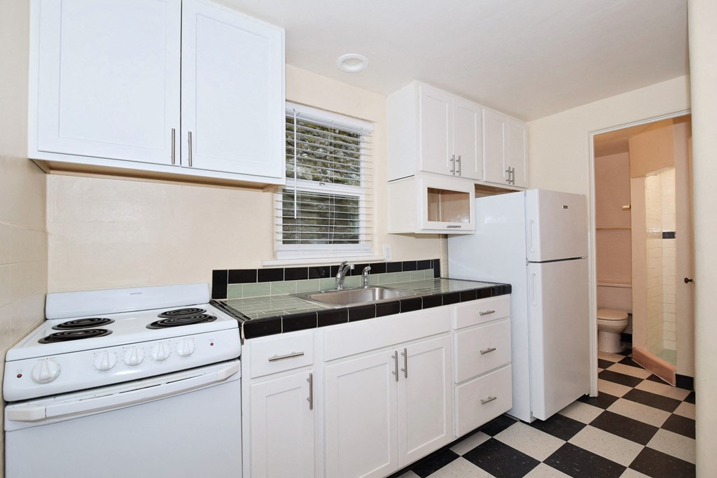 a kitchen with white appliances and a black and white checkered floor