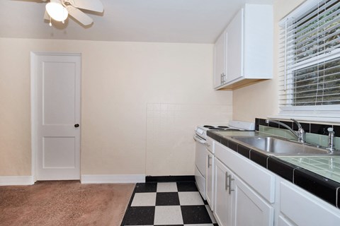 a kitchen with black and white checkered floor and white cabinets and a sink