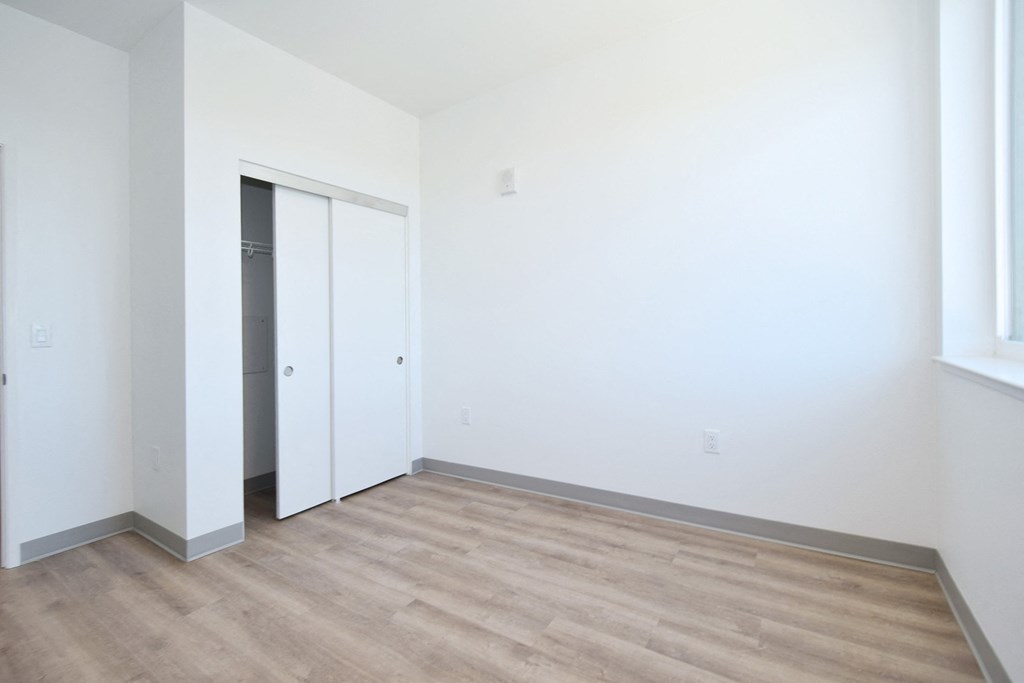 a bedroom with white walls and a wooden floor