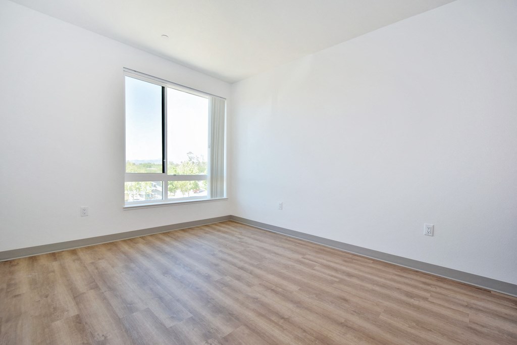 a bedroom with hardwood floors and a large window
