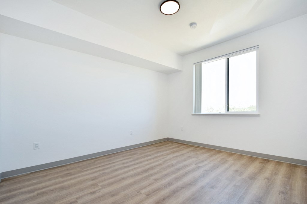 a minimal bedroom with white walls and hardwood floors