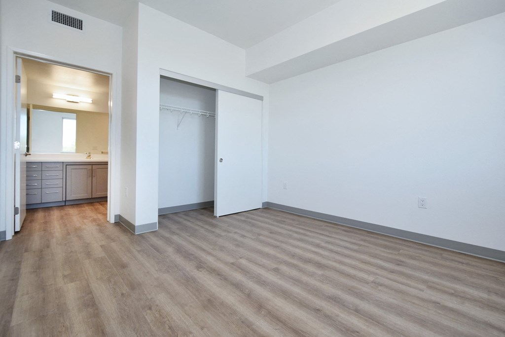 a bedroom with white walls and hardwood floors