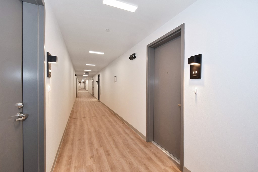 a long corridor with white walls and grey doors