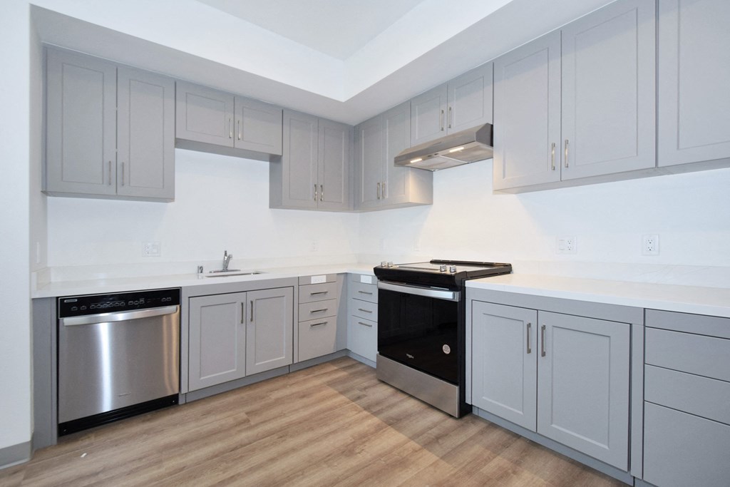 a kitchen with gray cabinets and a wooden floor
