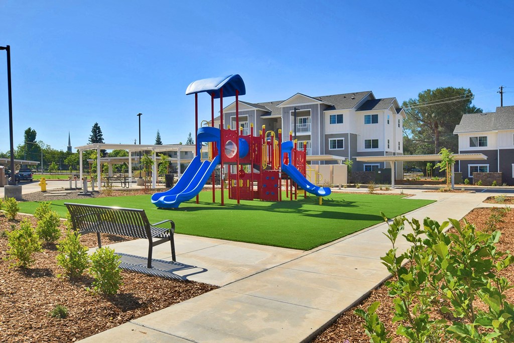 a playground with a swing set and a bench in front of an apartment building