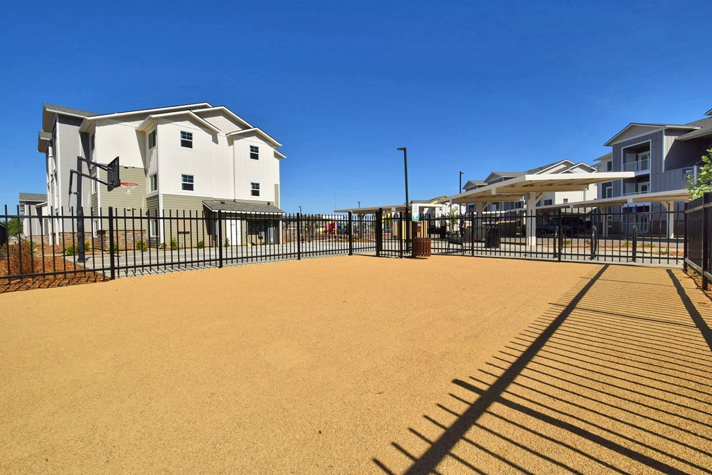 a fenced in area with apartment buildings in the background