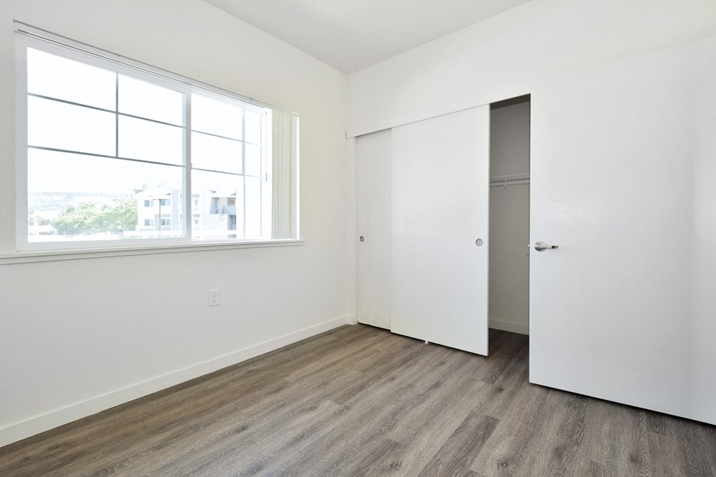 an empty bedroom with white walls and wood floors and a window