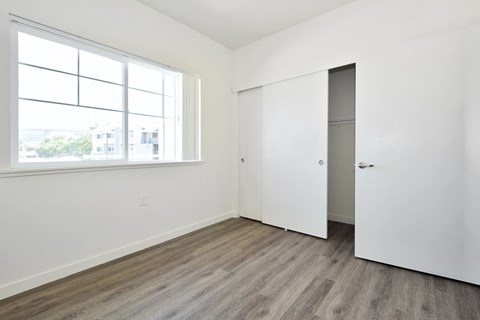 an empty bedroom with white walls and wood floors and a window