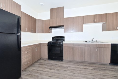 an empty kitchen with wooden cabinets and a black refrigerator