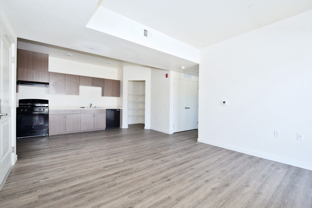 an empty living room and kitchen with white walls and wood flooring