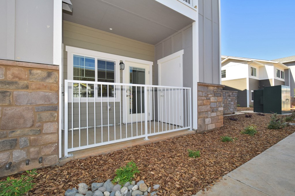 a porch with a white door and a stone wall