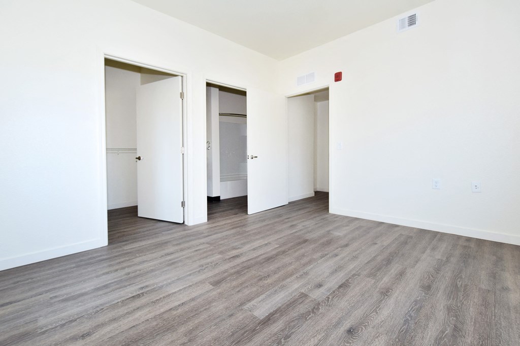 an empty room with white walls and wood flooring and doors