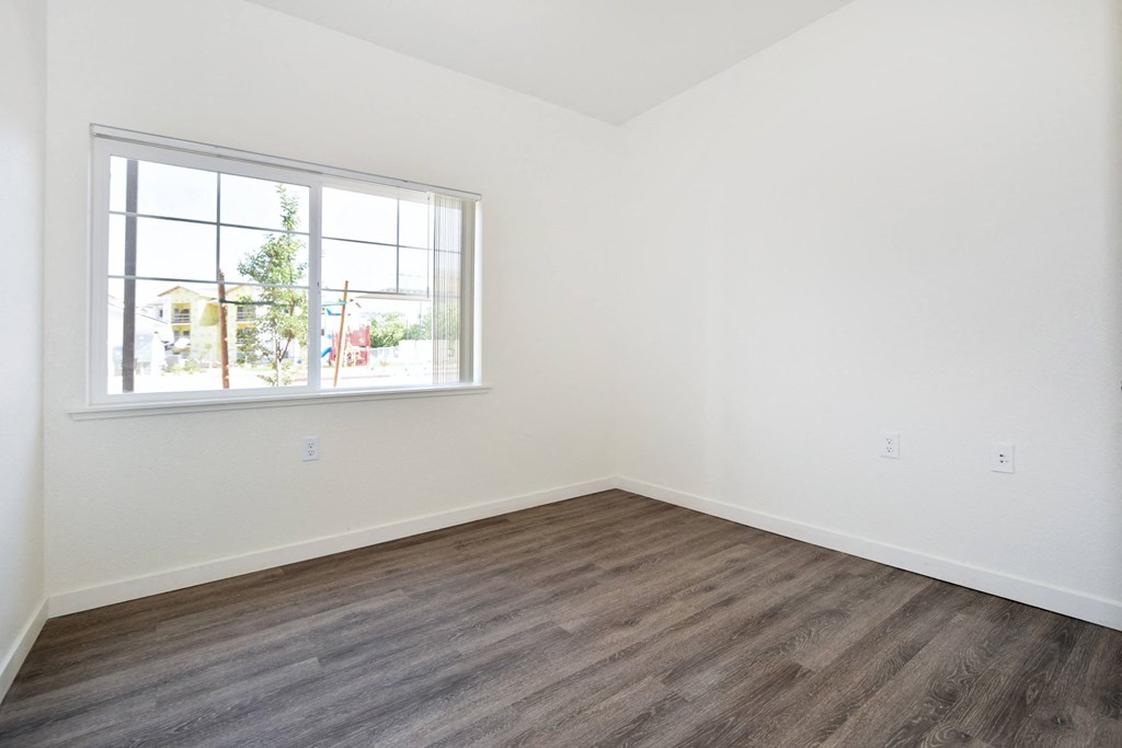 a bedroom with hardwood floors and a large window