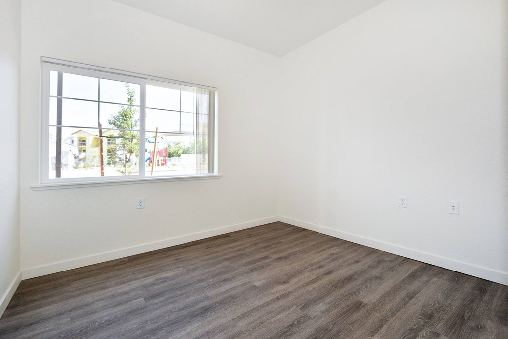 a bedroom with hardwood floors and a large window