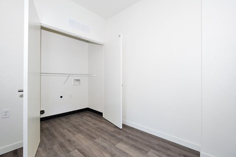 a bedroom with white walls and wood flooring and a closet