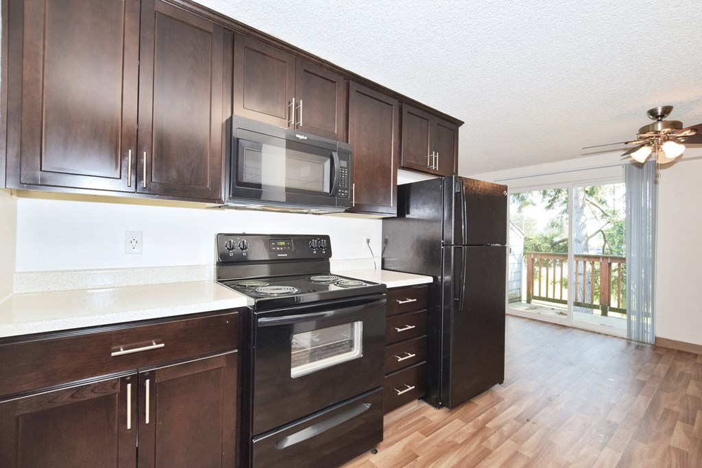 a kitchen with dark wood cabinets and white countertops