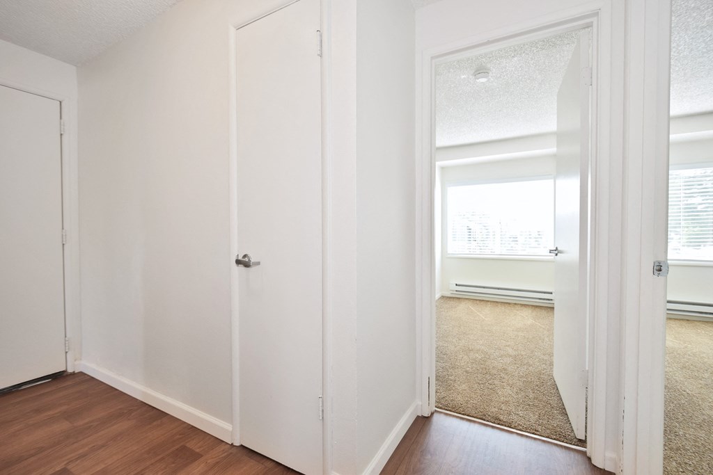 a bedroom with hardwood floors and white walls